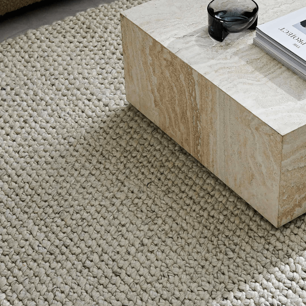 A close up of the Emerson chunky natural wool rug with a square coffee table on top.