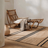 The Umbra natural brown rug with a cane seat sitting on top.