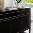 Black sideboard with decorative items including books and a plant in a modern interior setting.
