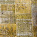 Close-up of a yellow and gray patchwork rug with floral patterns.