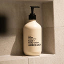Beige lotion bottle with black text on a tiled wall background