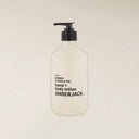 A frosted white pump bottle of Amberjack hand and body lotion with a black pump dispenser, centered against a light beige background.