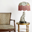 Decorative lamp with cheetah design on a small table next to a leopard print chair.