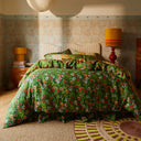 Bedroom with green, orange, and yellow floral bedding and patterned walls on the background