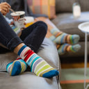 Two pairs of feet wearing colorful striped socks on a couch.