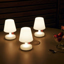 Three small white table lamps on a wooden surface with a dark background