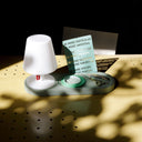 Small white lamp on a green wall mount base with a card and keys nearby