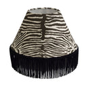 Lampshade crafted from Equus Cocoa with zebra pattern and black fringe on a white background