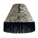 Lampshade crafted from Equus Cocoa fabric with zebra pattern and black fringes on a white background