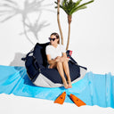 Woman sitting on a blue and gray beanbag with palm trees in the background