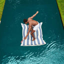 Person standing on a striped inflatable pool float in a pool