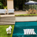 Outdoor setting with pool, striped floating beanbags, and garden area.