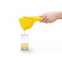 Yellow citrus squeezer being used to extract juice into a glass on a white background