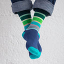 Colorful striped socks worn with rolled-up jeans on a light background