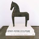 Wooden horse sculpture on a book titled 'Henry Moore Sculpture' with a plain background