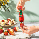 Person using a red strawberry huller on a plate of strawberries and cream desserts.