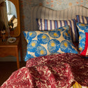 Bed with patterned bedding and pillows in a room with floral wallpaper.