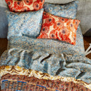 Decorative pillows with orange florals on a blue bedding set-up.
