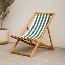 Wooden deck chair with green and white striped seat on a tiled floor.