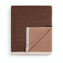 A folded throw blanket with a textured herringbone pattern, featuring a dark brown front side, a lighter dusty red reverse side, and cream-colored fringe trim.