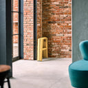 Modern interior with the Lucano 2-step mustard yellow stool folded against a brick wall and a blue chair.