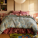 Bed with blue floral comforter and striped pillows in a bedroom setting.