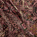 Close-up of a patterned fabric with intricate designs in shades of purple, green, and brown.