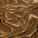 A close-up of draped brown velvet fabric with soft folds and a plush texture.