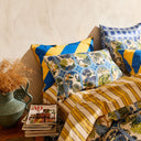 Decorative pillows with blue, yellow, and floral patterns on a sofa against a beige wall.