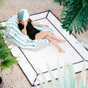 Person lounging on a blue striped pool float with tropical plants around