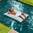 Man lying on a blue striped pool floating beanbag in a swimming pool