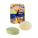 Two soap bars and a decorative tin with 'Ortigia' branding on a white background