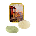 Two soaps in front of a decorative tin labeled 'Ortigia Roma' on a white background