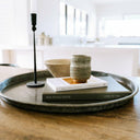 Decorative tray with a candle, bowl, and books on a wooden surface.