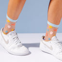 White sneakers with colorful polka dot socks on a light blue background