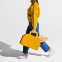 Person holding a yellow bag with bread against a white background