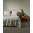 Neatly made bed with white bedding and pillows in a minimalistic bedroom setting.