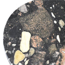 Close-up of a round, black surface with embedded stones and pebbles