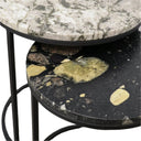 Round marble table with a black and gold speckled design on a light gray floor.