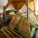 Bed with canopy and patterned bedding in green and yellow in a cosy room