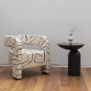 Modern chair with abstract pattern next to a smokey black stone side table on a wooden floor.