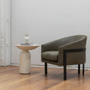 Modern chair and smokey white stone side table in a minimalistic room with wooden floor and white walls.