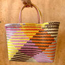 Colorful woven bag held by a hand on a wooden surface