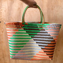 Handheld woven bag with geometric pattern on a wooden surface
