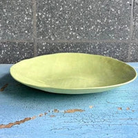 Side on view of a green ceramic side plate.