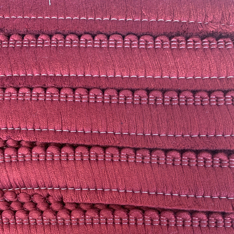 A close up of a burgundy cushion fringe.