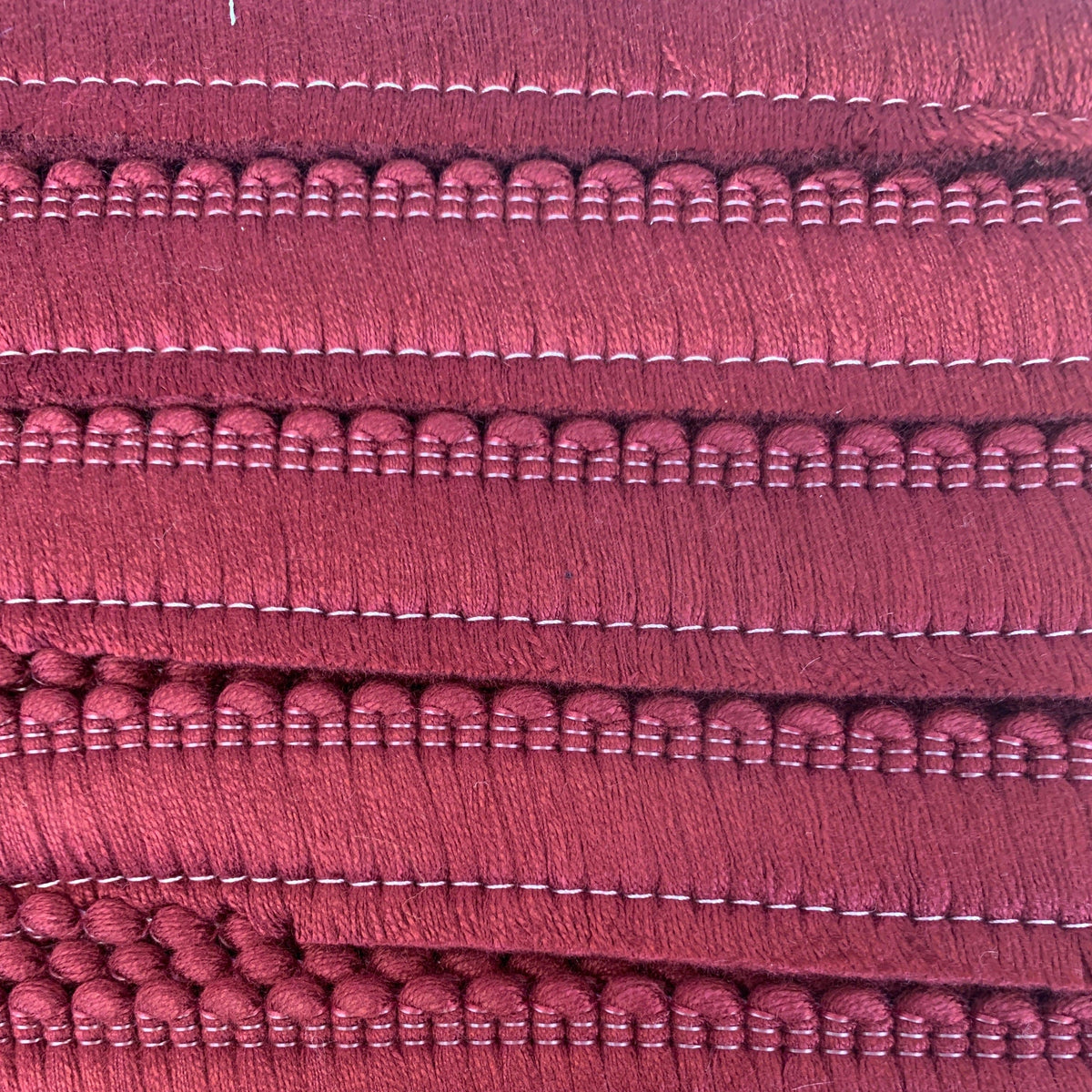 A close up of a burgundy cushion fringe.