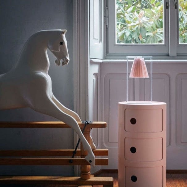 A pink pleated table lamp in a child's bedroom.