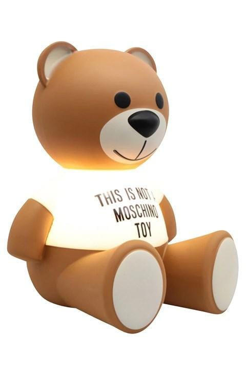 A teddy lamp that says 'this is not a moschino toy' on it's white t-shirt.