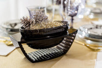 A smoke grey centrepiece with pinecones and gold shavings on top.
